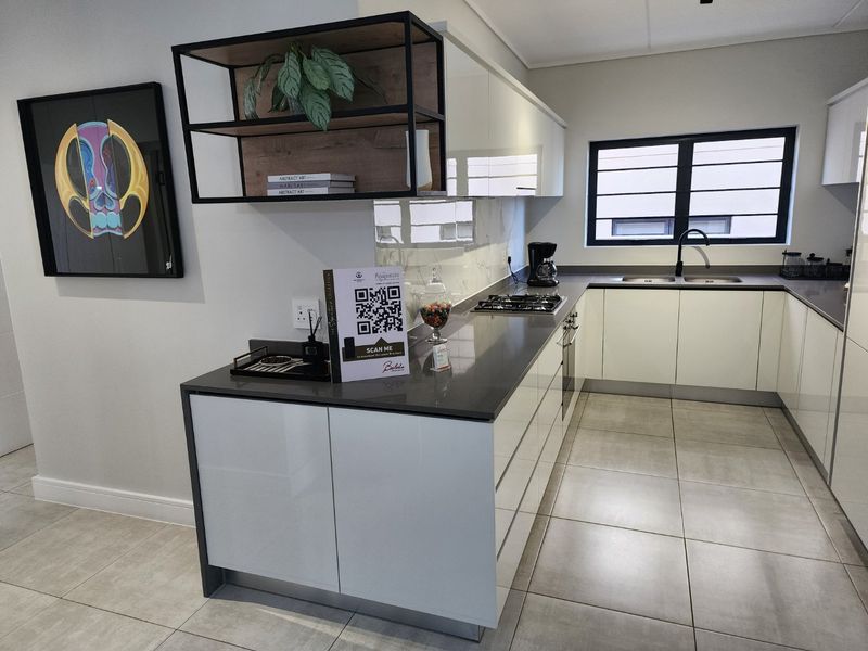 Modern kitchen featuring high-gloss cabinetry, stone countertops, a gas hob, built-in oven, and a double basin sink with a contemporary mixer tap.