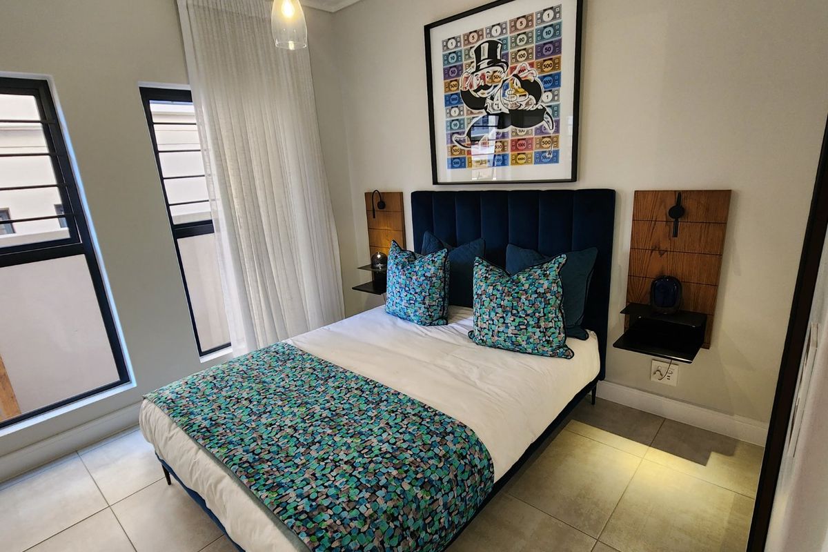 A well-maintained bedroom featuring neutral tiled flooring, modern aluminium window frames, and custom wall-mounted bedside shelving units.