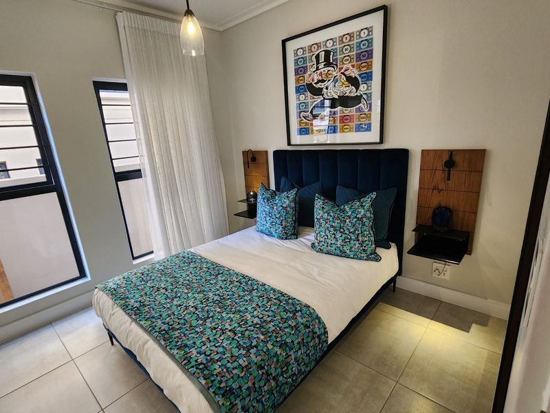 A well-maintained bedroom featuring neutral tiled flooring, modern aluminium window frames, and custom wall-mounted bedside shelving units.