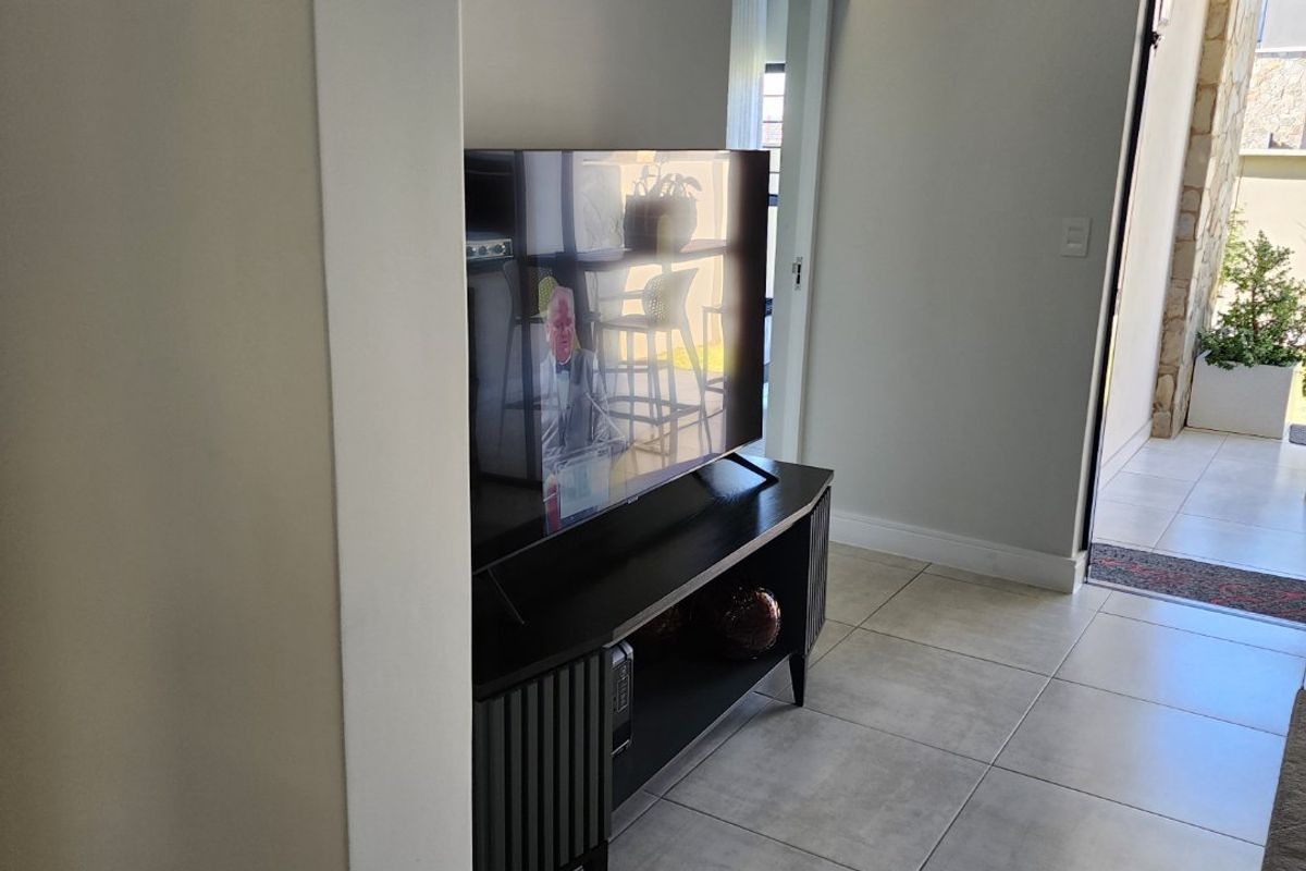 A modern living area featuring neutral tiled flooring, clean white walls, and recessed ceiling lighting, with direct access to an outdoor patio space.