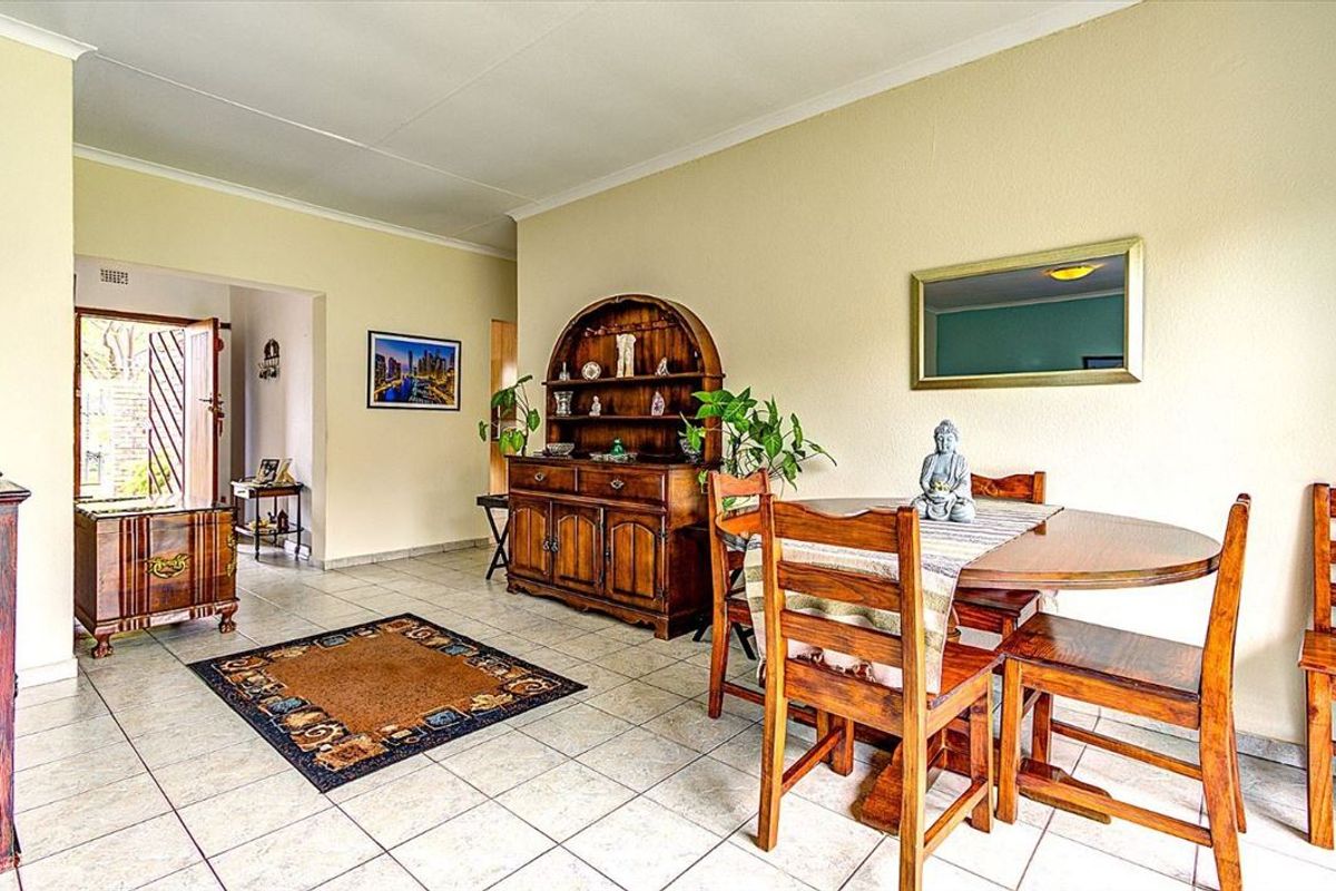 A dining area featuring neutral wall tones and ceramic tile flooring, providing a functional space with direct access to the home entrance.
