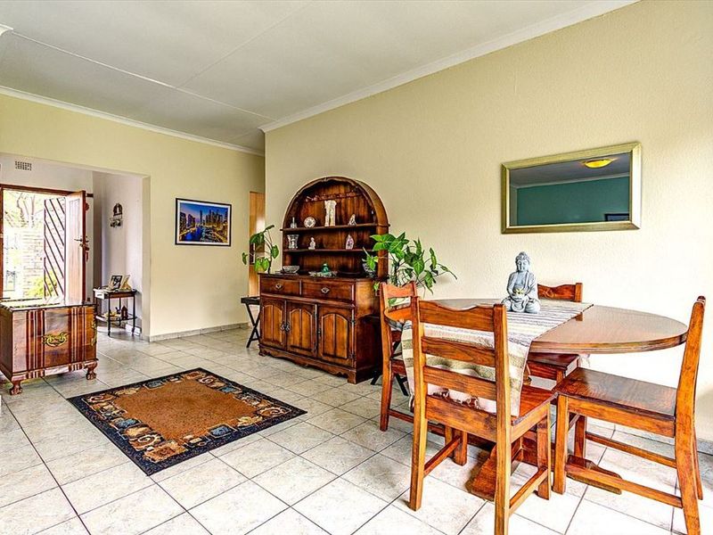 A dining area featuring neutral wall tones and ceramic tile flooring, providing a functional space with direct access to the home entrance.