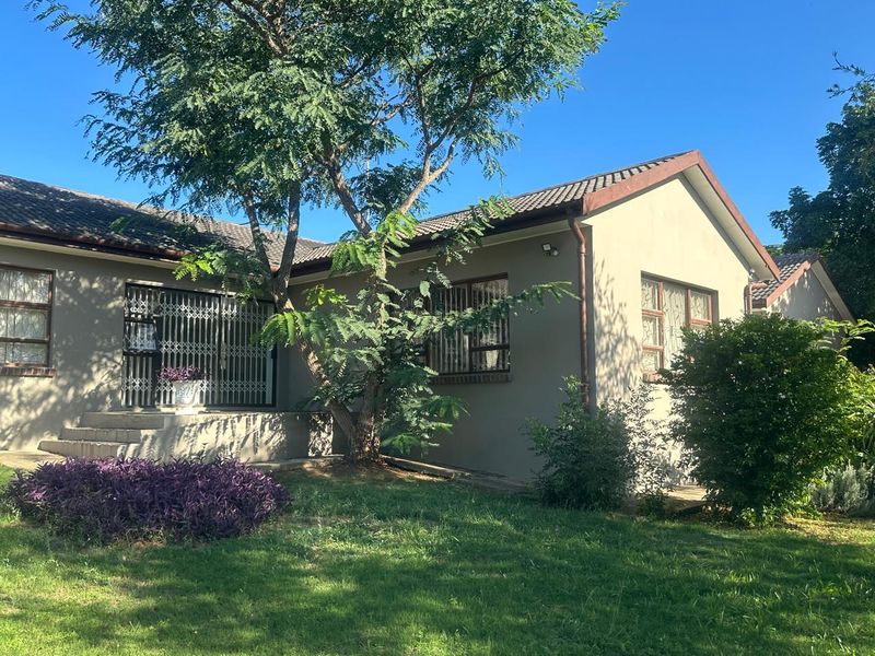 Rear view of the house featuring a tiled roof, security gates, and concrete steps leading to the entrance, set within a landscaped garden.