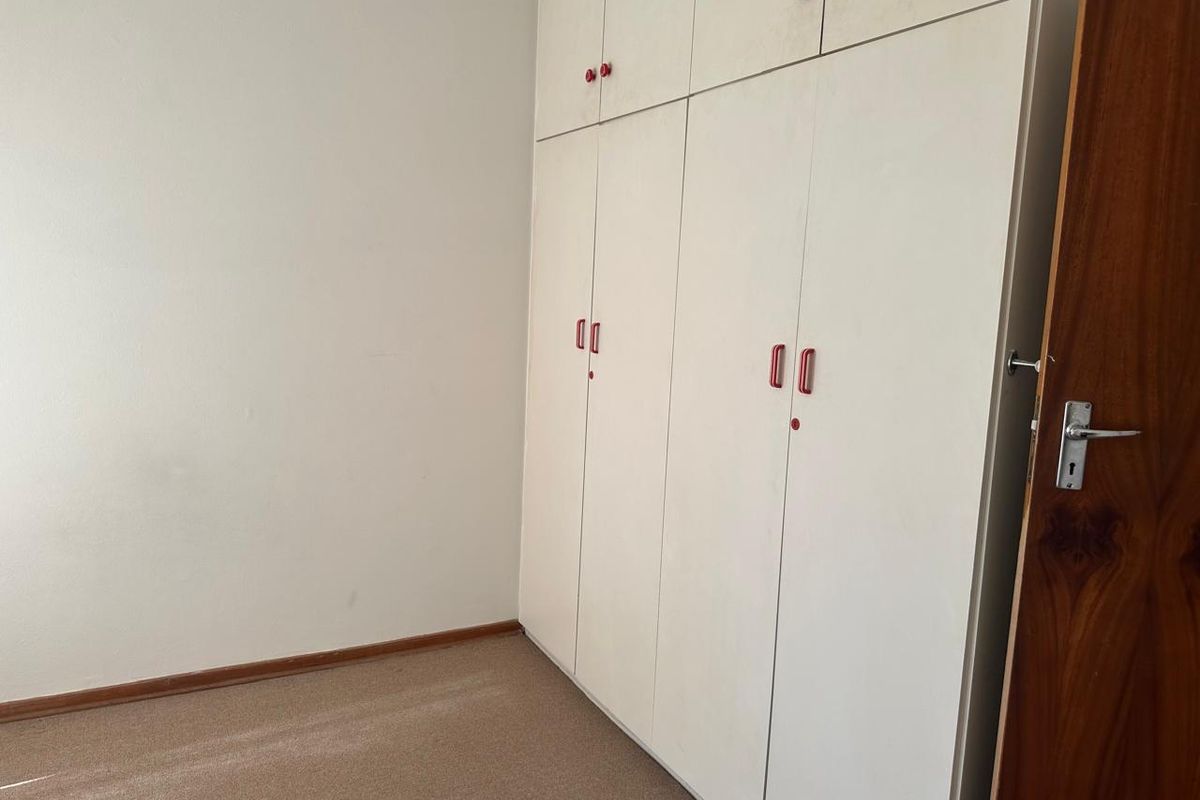 A vacant bedroom featuring built-in cupboards and carpeted flooring, offering a blank canvas for potential updates and interior design improvements.