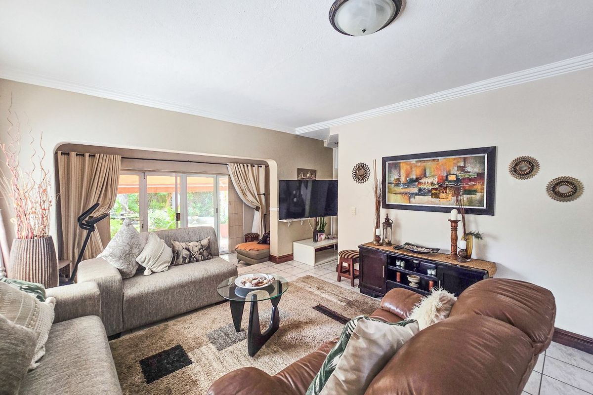 Spacious living room featuring tiled flooring, coved ceiling details, and large sliding glass doors providing direct access to the outdoor patio area.