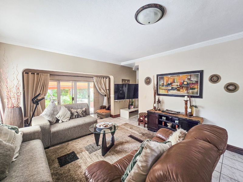 Spacious living room featuring tiled flooring, coved ceiling details, and large sliding glass doors providing direct access to the outdoor patio area.