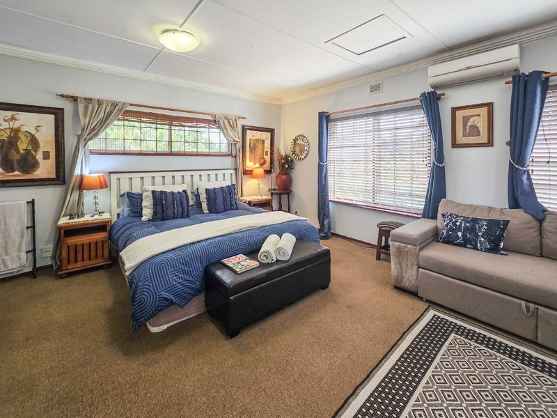 Spacious bedroom featuring neutral wall tones, carpeted flooring, timber blinds, and a wall-mounted split-system air conditioning unit.
