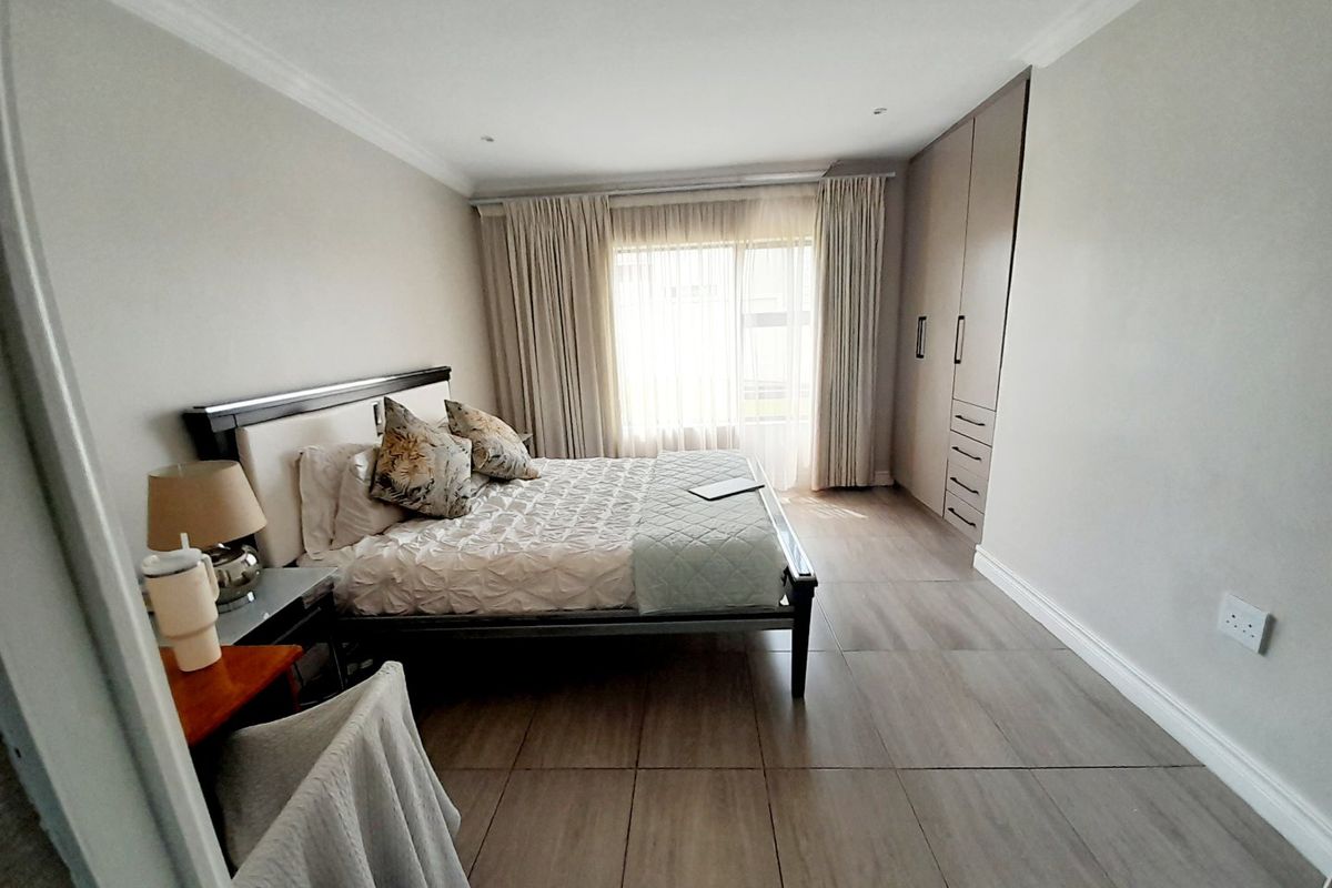 A well-maintained bedroom featuring neutral tiled flooring, built-in cupboards, and elegant cornicing, offering a clean and comfortable living space.