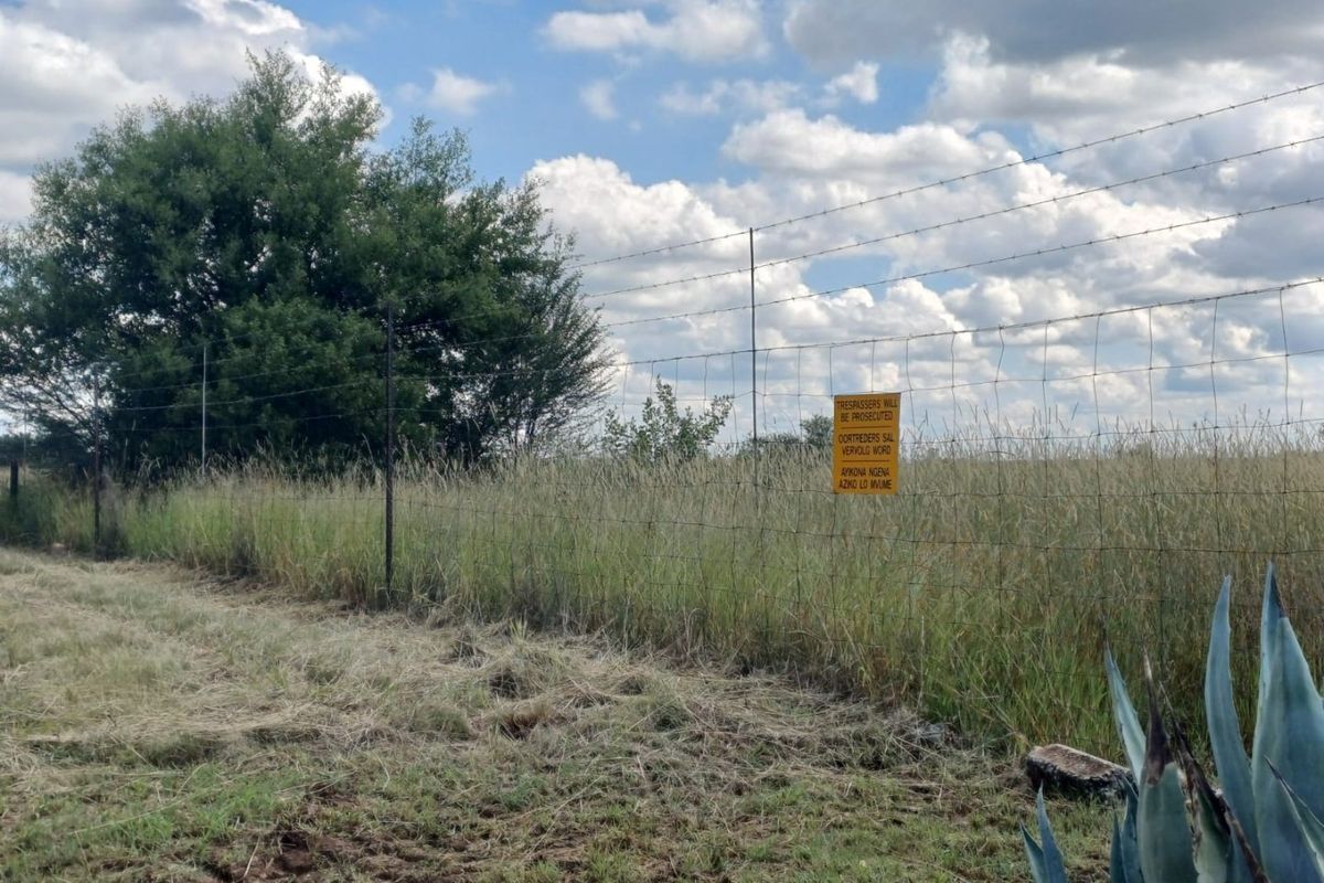 A view of the farm perimeter featuring a wire fence and signage bordering the open field.