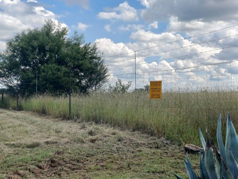 A view of the farm perimeter featuring a wire fence and signage bordering the open field.