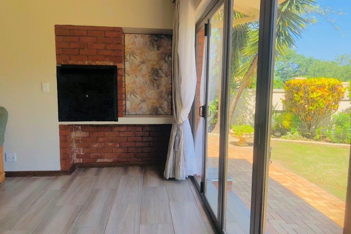 Living area featuring a built-in brick fireplace and large sliding glass doors providing seamless access to the outdoor patio and garden.