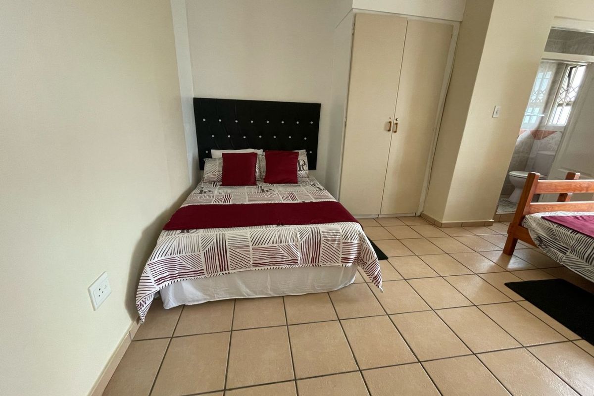 A bedroom featuring ceramic floor tiles, a built-in wardrobe, and direct access to an en-suite bathroom.