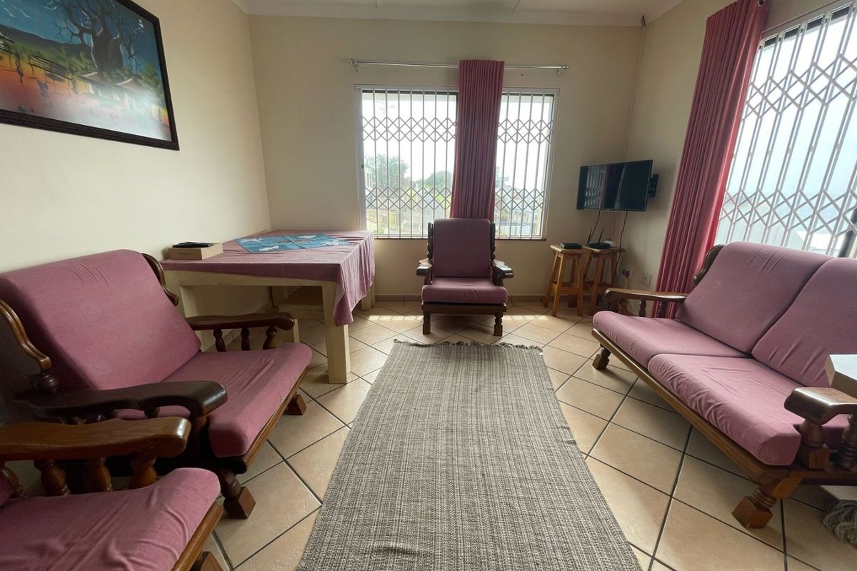 A living room featuring ceramic floor tiles, security gates on windows, and coving, providing a functional and well-lit space.