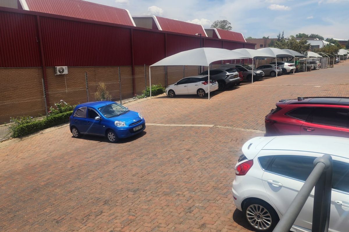 Commercial property exterior featuring a paved parking area with shade cloth carports, brick walling, and secure electric fencing.
