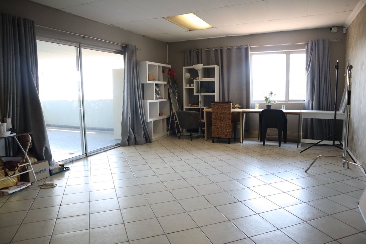 Spacious living area featuring tiled flooring, recessed lighting, and a large sliding glass door providing access to an outdoor balcony.