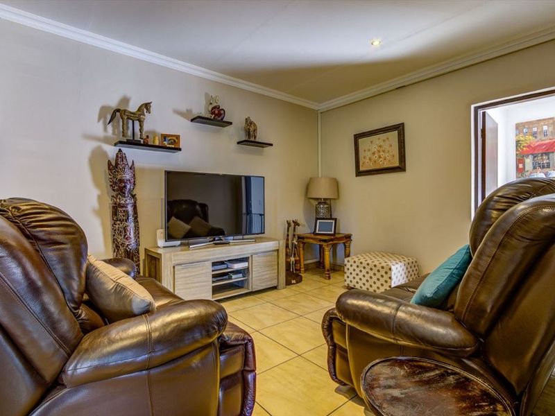 A comfortable living room featuring tiled flooring, recessed downlighting, and decorative cornice detailing, providing a functional and well-maintained space.