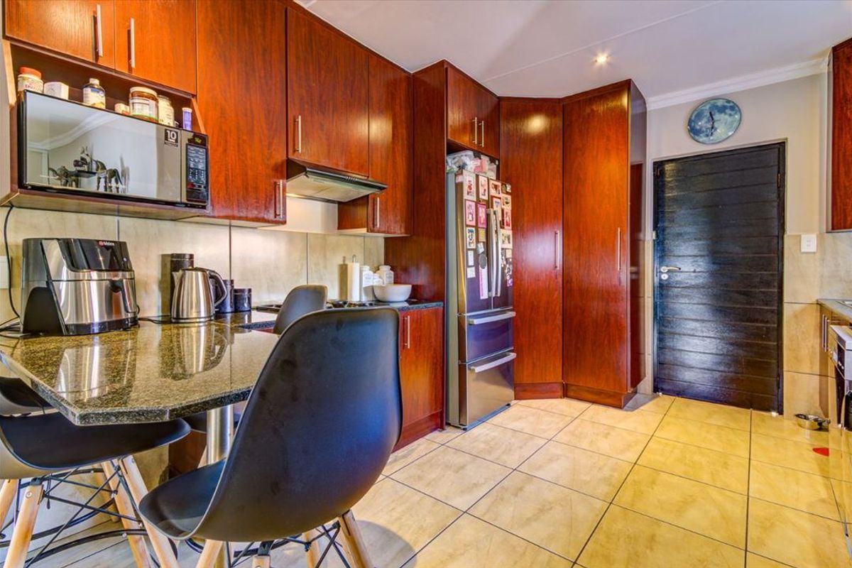 A functional kitchen featuring dark wood cabinetry, granite countertops, tiled flooring, and integrated storage solutions.