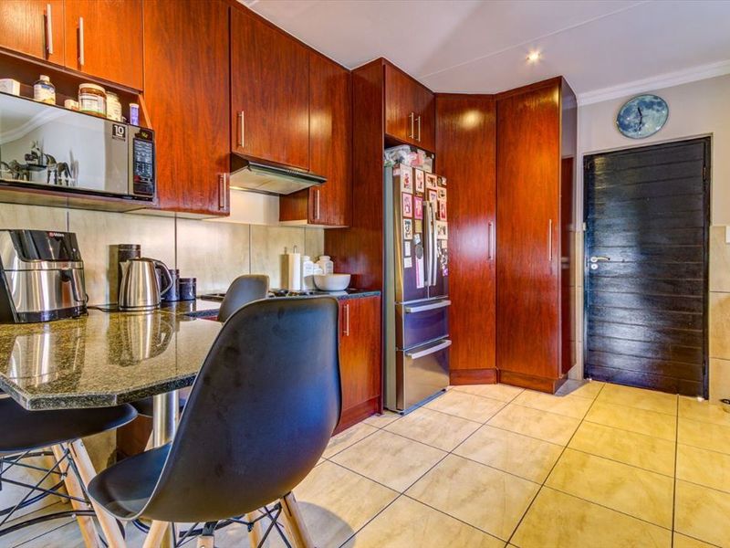 A functional kitchen featuring dark wood cabinetry, granite countertops, tiled flooring, and integrated storage solutions.