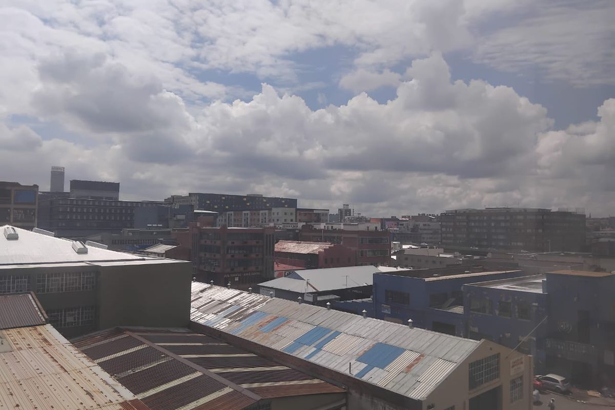 Elevated view overlooking an industrial urban landscape featuring various commercial buildings with corrugated metal roofing.