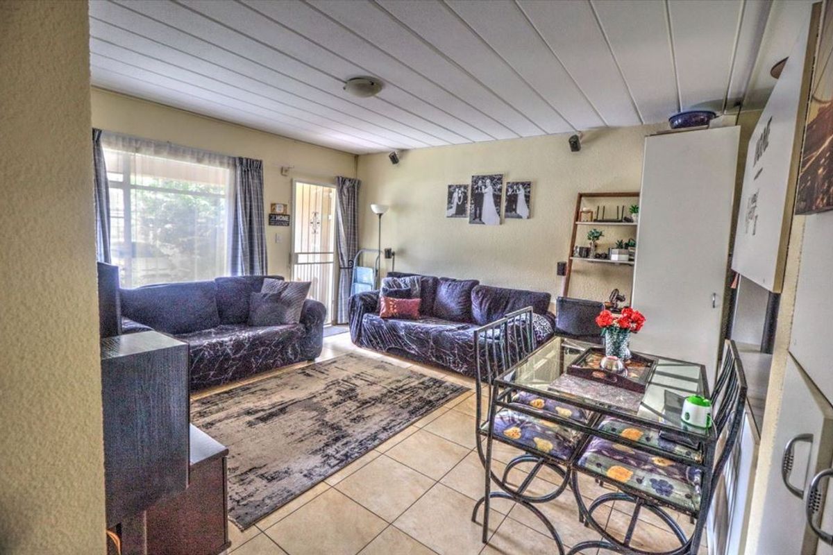 Open-plan living and dining area featuring tiled flooring, a panelled ceiling, and direct access to the exterior through a sliding glass door.