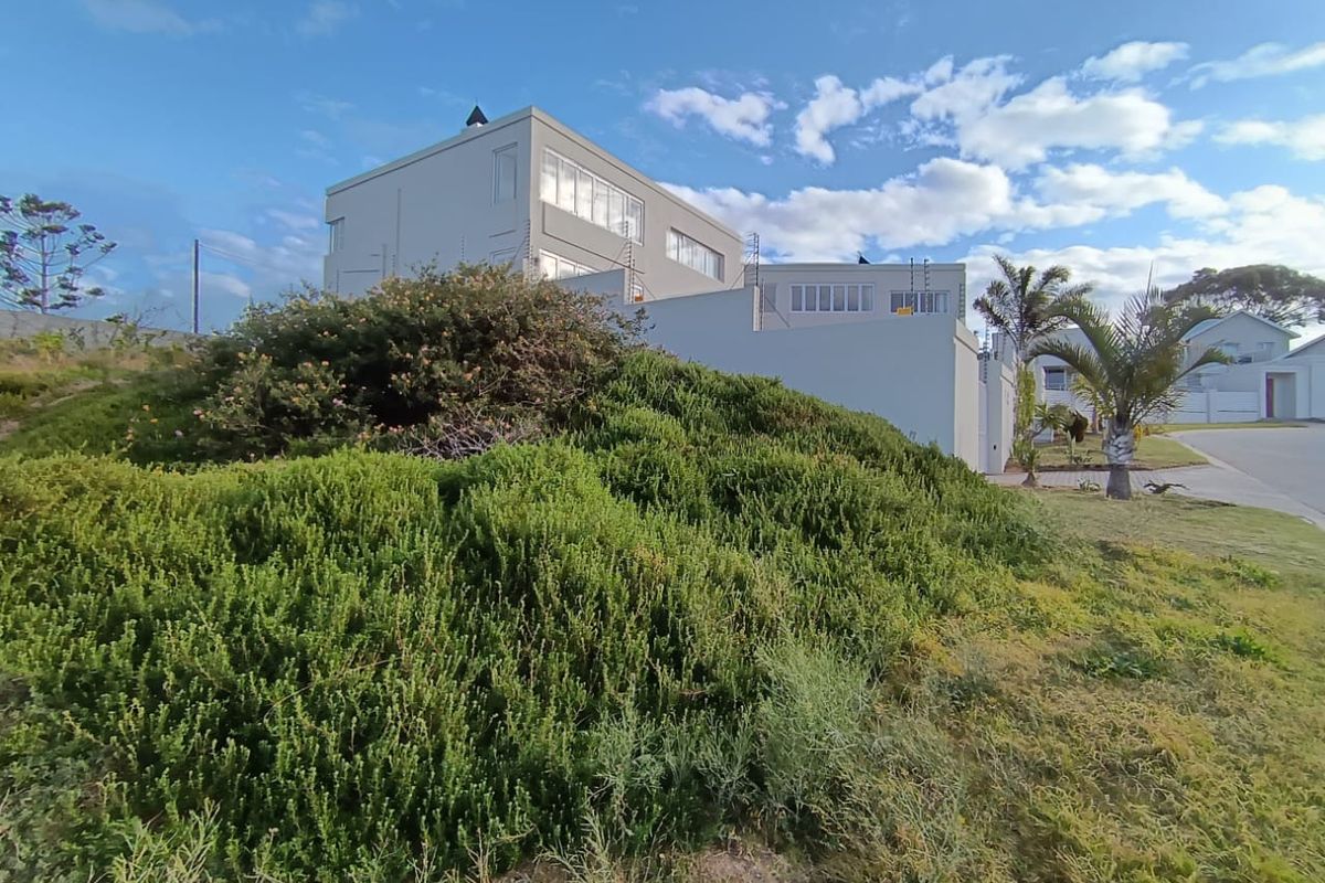 A view of the front facade of a modern residential property featuring a landscaped garden and paved driveway.