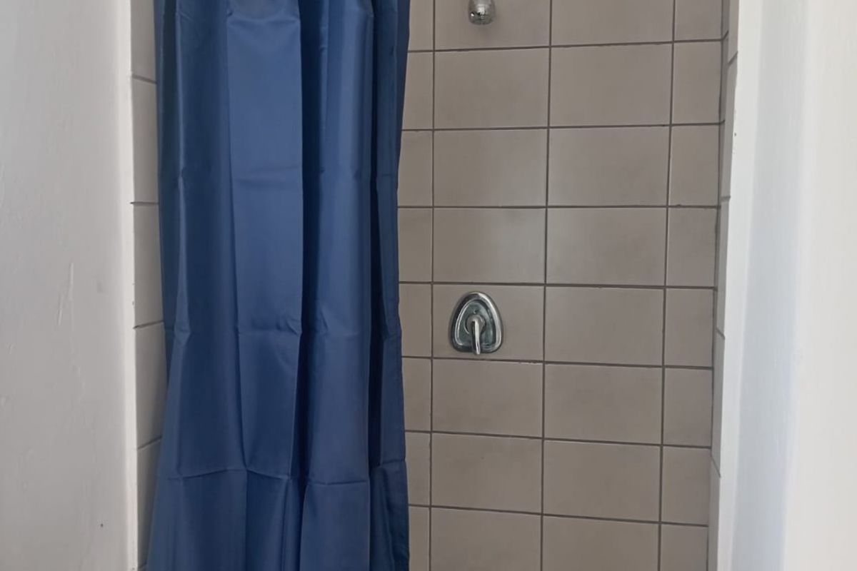 A functional shower enclosure featuring tiled walls and standard chrome fixtures, currently requiring cosmetic updates to improve the overall aesthetic.