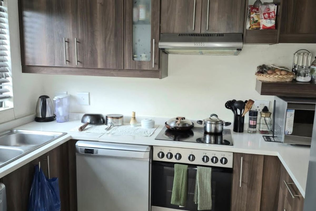 A functional kitchen featuring dark wood-look cabinetry, stone countertops, a built-in oven with electric hob, and a stainless steel extractor fan.