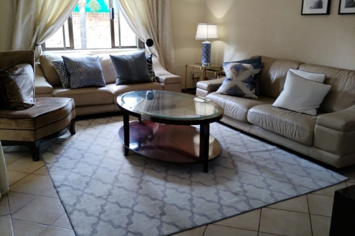 A comfortable living room featuring ceramic tile flooring, a wall-mounted split-system air conditioner, and neutral wall finishes.
