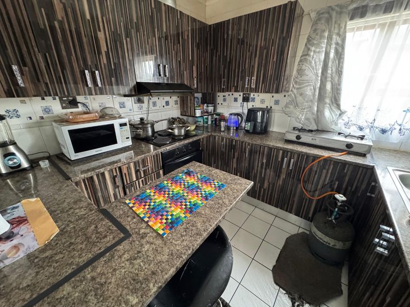 A functional kitchen featuring granite countertops, laminate cabinetry, and tiled flooring, offering a practical layout with built-in cooking appliances.