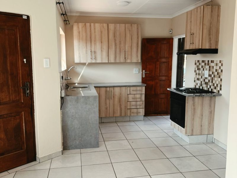 A functional kitchen featuring light wood-look cabinetry, tiled flooring, a built-in oven with gas hob, and a tiled splashback.