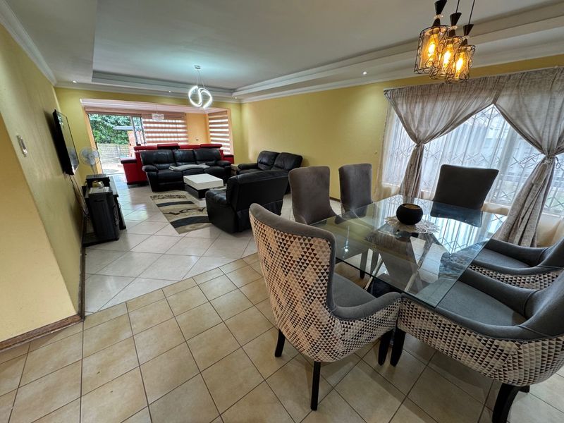 Spacious open-plan living and dining area featuring tiled flooring, recessed ceiling lighting, and large sliding doors providing access to the outdoor space.