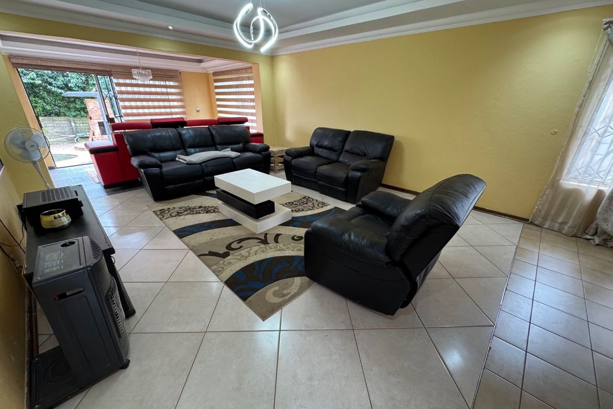 Spacious living room featuring tiled flooring, a recessed ceiling, and large sliding glass doors providing access to the outdoor patio area.
