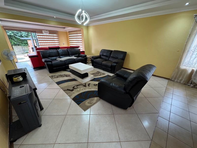 Spacious living room featuring tiled flooring, a recessed ceiling, and large sliding glass doors providing access to the outdoor patio area.