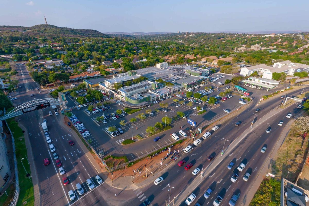 Aerial view of a commercial shopping center featuring extensive parking facilities, solar panel installations, and convenient access from the surrounding main roads.