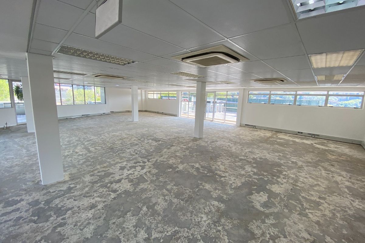 A spacious, open-plan commercial office area featuring a suspended ceiling, integrated air conditioning, and large windows providing ample natural light.