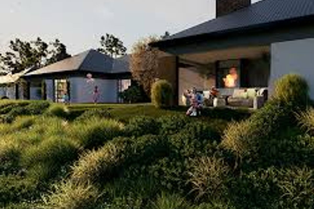 A rear view of a modern house featuring a covered patio area, brick chimney, and extensive landscaped garden.