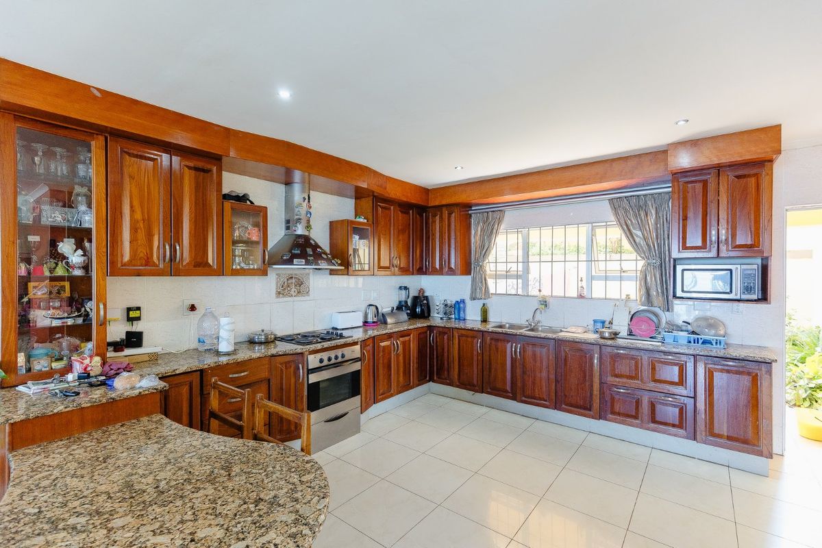 Spacious kitchen featuring solid wood cabinetry, granite countertops, built-in oven, gas hob, and tiled flooring with ample workspace.