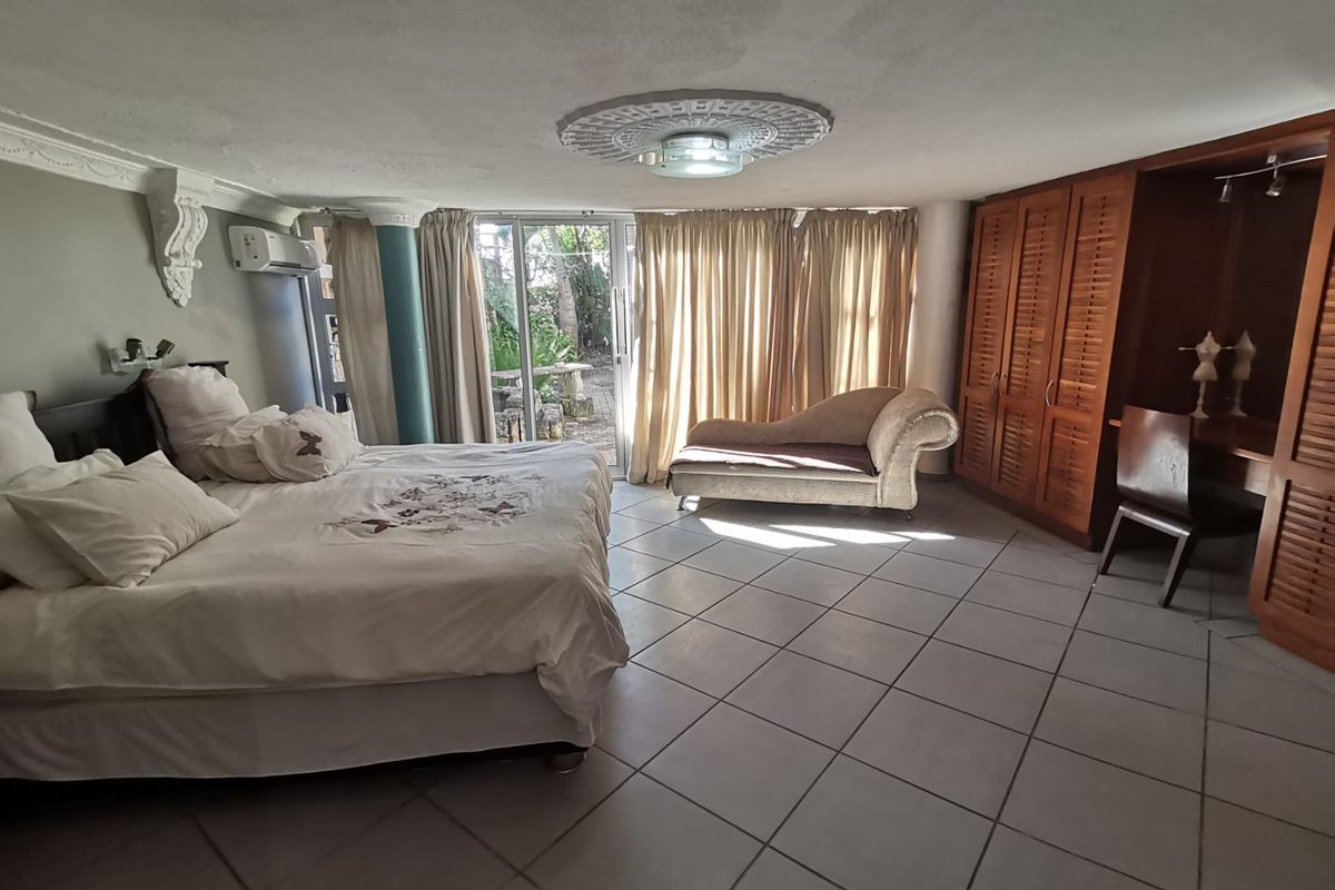 Spacious bedroom featuring built-in wooden cabinetry, tiled flooring, air conditioning, and direct access to an outdoor patio area through sliding glass doors.