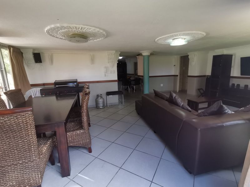 Spacious open-plan living and dining area featuring ceramic floor tiles, decorative ceiling medallions, and a structural column, offering a versatile layout for modern living.