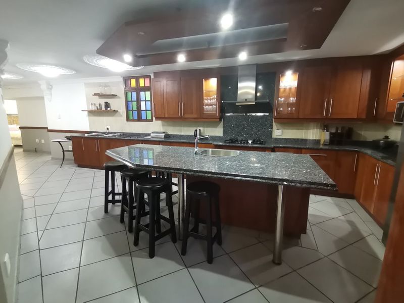Spacious kitchen featuring dark wood cabinetry, granite countertops, a central island with seating, and integrated stainless steel appliances.