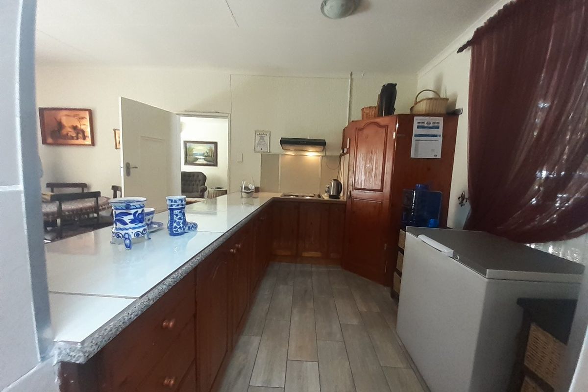 A functional kitchen featuring wooden cabinetry, laminate countertops, and tiled flooring, offering a traditional layout with potential for modern updates.
