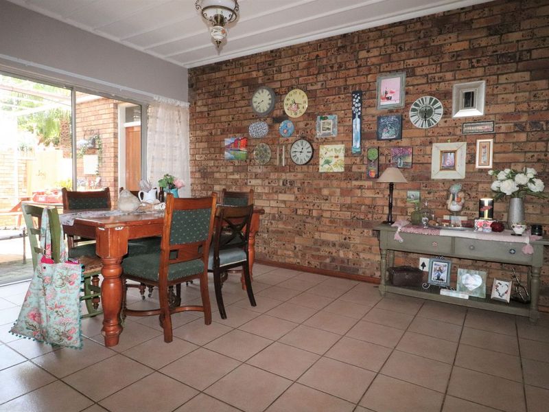 Dining area featuring an exposed brick wall, ceramic floor tiles, and a sliding glass door providing access to the outdoor patio.