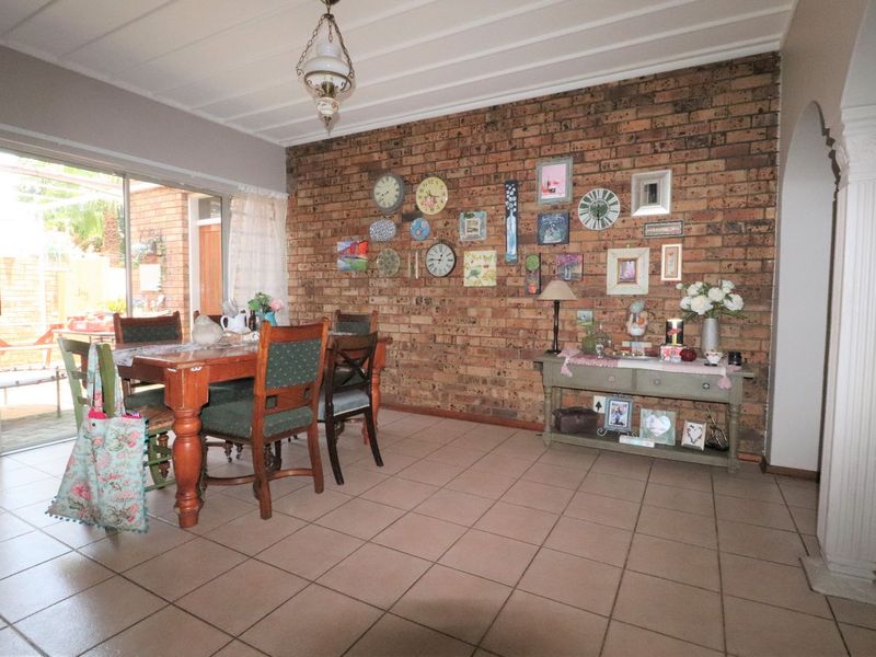 Dining area featuring an exposed brick feature wall, tiled flooring, and a sliding glass door providing access to the outdoor patio.
