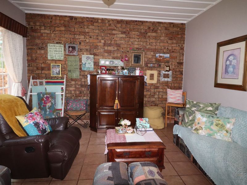 A living room featuring an exposed brick feature wall, tiled flooring, and a tongue and groove ceiling.