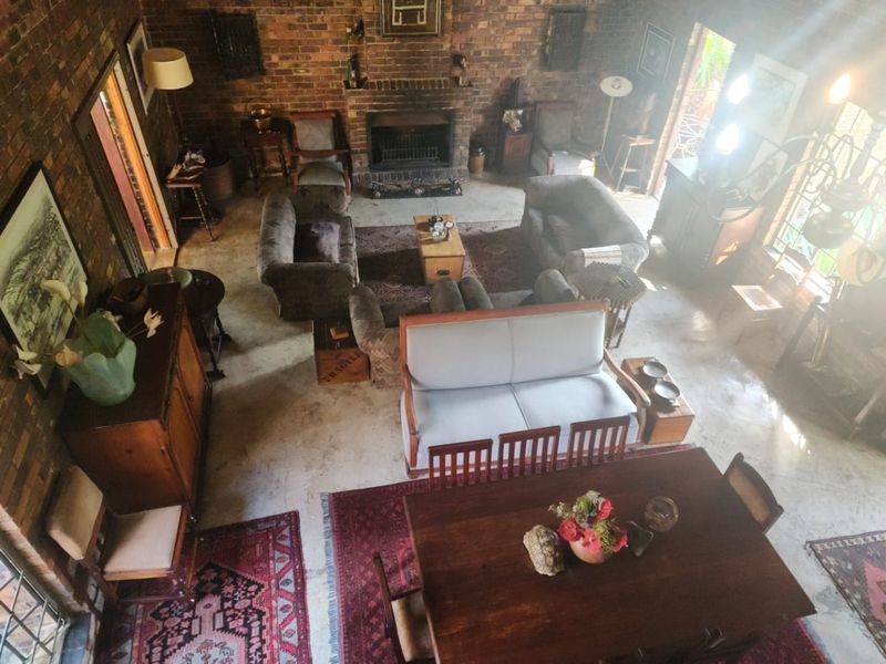 Spacious open-plan living and dining area featuring rustic exposed brick walls, a central built-in fireplace, and polished concrete flooring.
