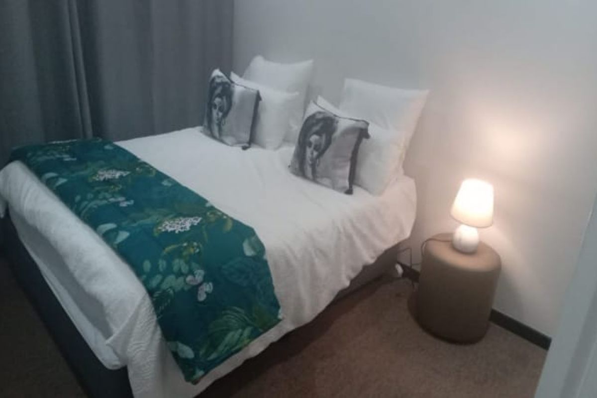 A compact bedroom featuring neutral wall finishes and carpeted flooring, providing a functional sleeping space.
