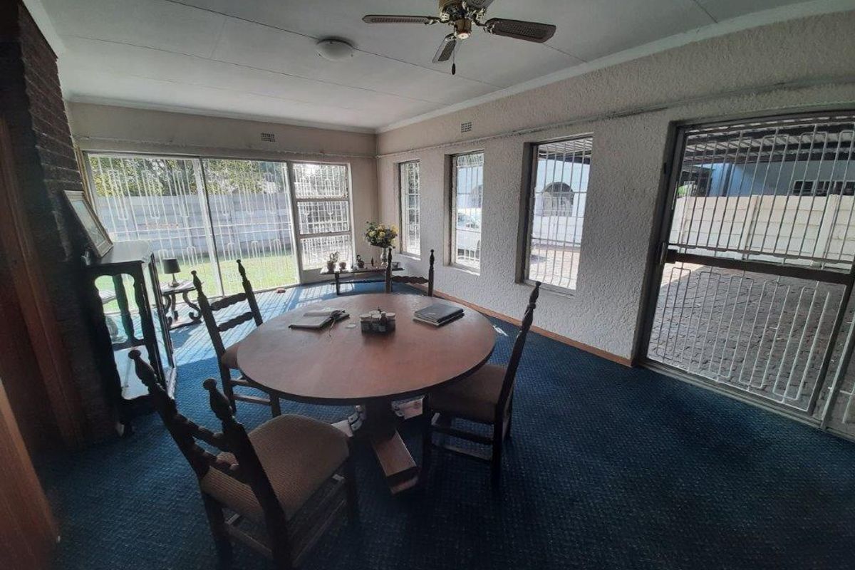 A living room featuring a brick fireplace, ceiling fan, and large sliding doors with security gates, offering direct access to the outdoor area.