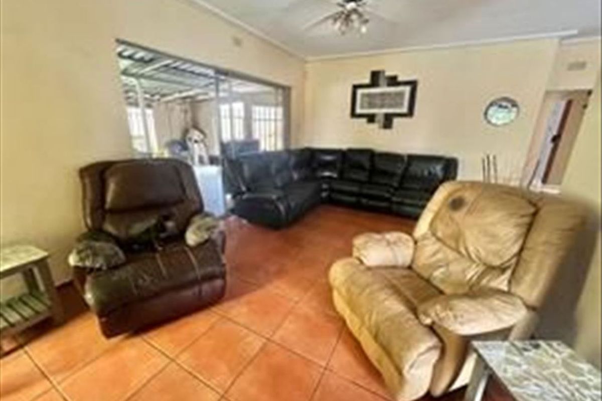 A living room featuring ceramic tile flooring, a ceiling fan, and a sliding glass door providing access to an adjacent outdoor area.