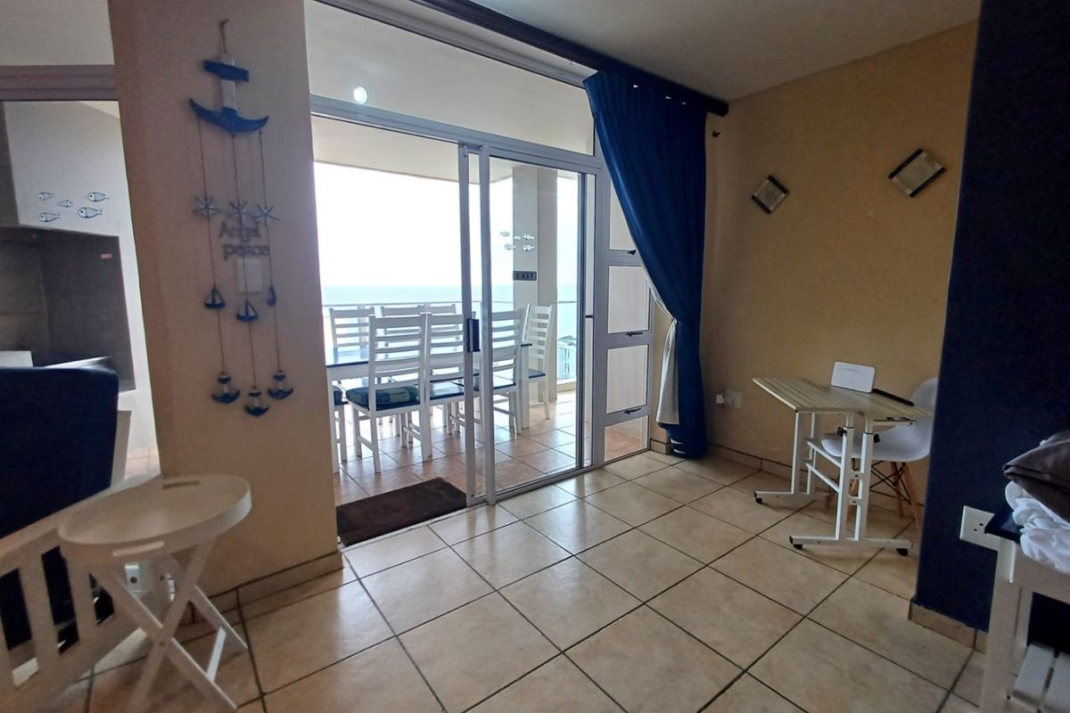 Living area featuring tiled flooring and a large sliding glass door providing access to an outdoor balcony with ocean views.