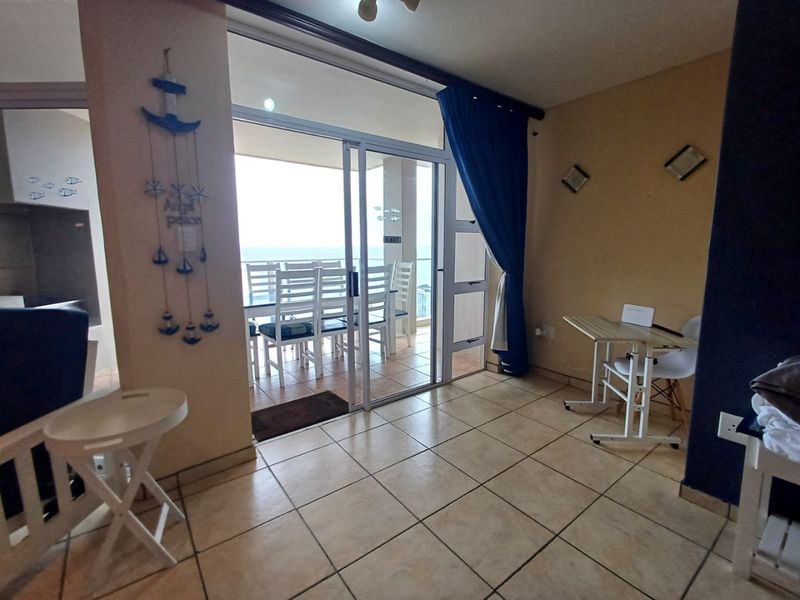 Living area featuring tiled flooring and a large sliding glass door providing access to an outdoor balcony with ocean views.